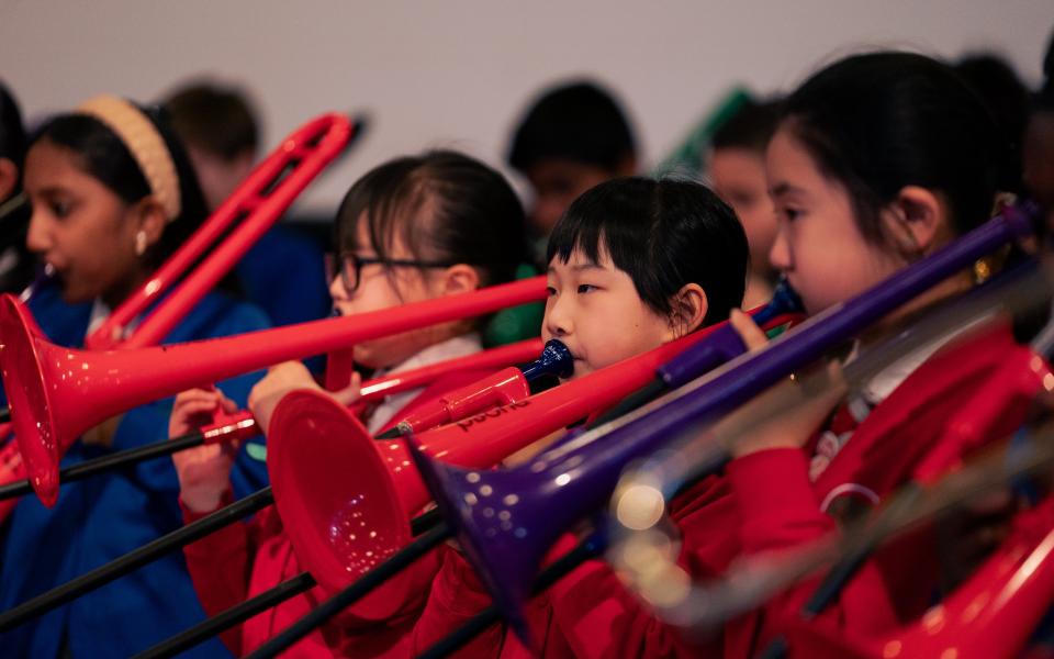 School kids playing plastic trumpets