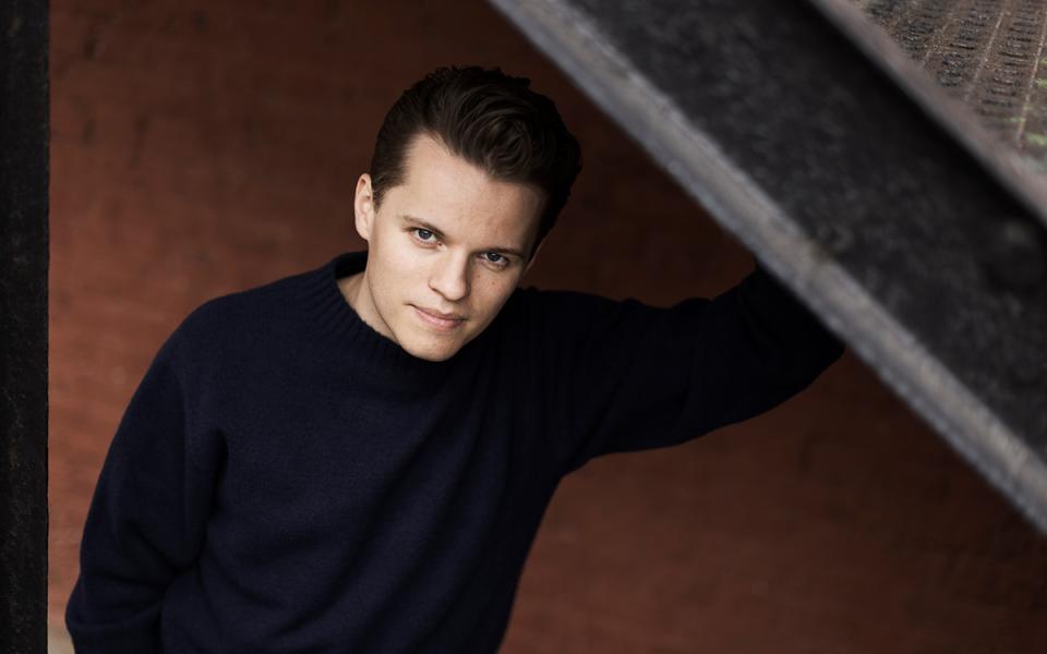 Adam Hickox leaning on a wall and looking up at the camera