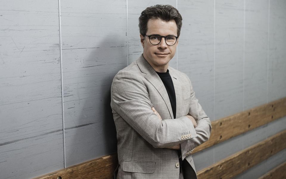 Jakub Hrusa leaning up against the wall, arms crossed looking at the camera