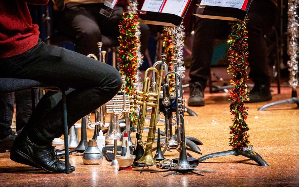 Trumpets stood up on the floor, with tinsel around music stands beside them
