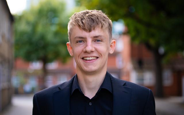 Will Kidner, Philharmonia Instrumental Fellow, smiling at the camera outside Philharmonia office